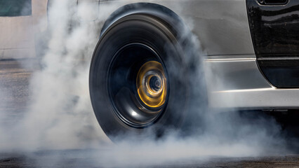 Car burnout wheels tire with white smoke,Car wheel burnout with smoke from the spinning tyre, Drag car wheel burns tires preparation for the race.