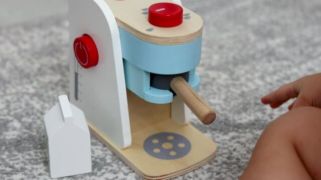 adorable baby playing with toy espresso machine. kid child putting cup, coffee, pretend to drink. coffee maker made from eco wood, safe creative roll play toys.boy sitting on floor 4k