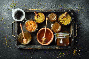 Set of honey, bee products and honeycomb honey. On a dark background. Top view. In a wooden box. - obrazy, fototapety, plakaty