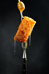 Honey stick and Honeycombs on a metal fork. Macro photo. Organic honey.
