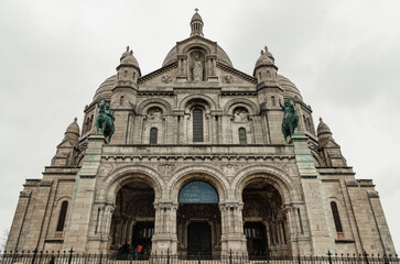 Fototapeta na wymiar The Roman Catholic church Sacr-Coeur Basilica in Montmartre with the bronze statues of Joan of Arc and Louis IX on either side, Romano-Byzantine architecture constructed in travertine. Space for text,
