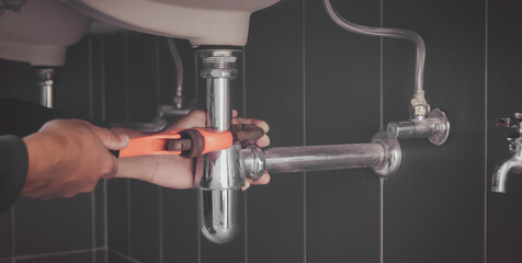 plumber at work in a bathroom, plumbing repair service , fix water plumbing leaks, replace the kitchen sink drain