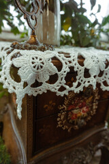 A wooden jewelry box with a floral pattern. From above, the casket is covered with white woven netting.
