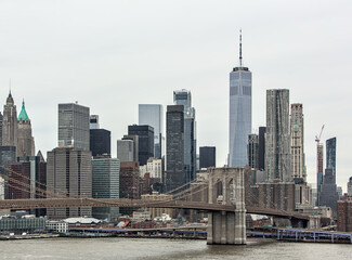 nyc skyline with brooklyn bridge and one world trade center (gray sky, cloudy overcast day)...