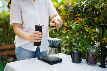 Happy Asian beautiful woman making a specialty coffee in morning at her backyard garden, woman brewing a coffee by dripping or pouring over a hot water.