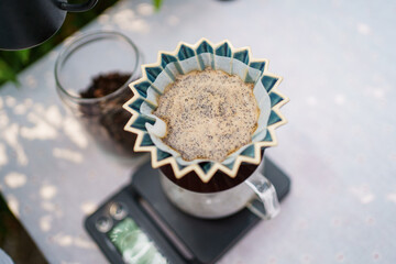 Happy Asian beautiful woman making a specialty coffee in morning at her backyard garden, woman brewing a coffee by dripping or pouring over a hot water.