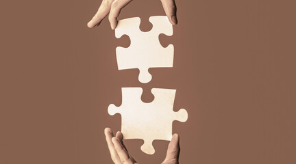 Closeup hands of man connecting jigsaw puzzle. Two hands trying to connect couple puzzle. Hand connecting jigsaw puzzle. Man hands connecting couple puzzle piece - obrazy, fototapety, plakaty