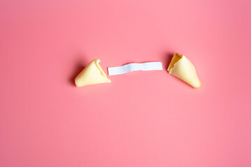 An open fortune cookie on a pink background. The concept of luck, lottery. Chinese New Year.