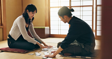 Man, woman and game with Japanese cards on floor in challenge, contest or problem solving with...