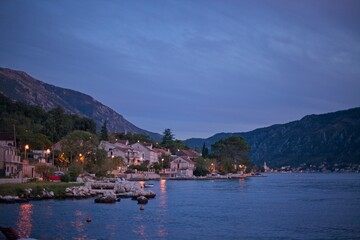 Fototapeta na wymiar As evening falls, the tranquil seaside village of Kotor is softly illuminated, with the calm waters of the bay reflecting the last light of day.