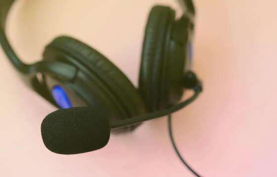 Black headphones lies on a colorful pastel pink background. Music listening concept - Powered by Adobe