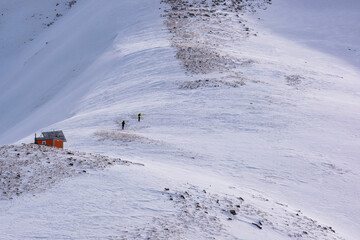 A group of people in sports equipment climb a snowy slope to the top of a mountain. Winter mountaineering is located near Almaty. Climbing to the top of the mountain in winter.