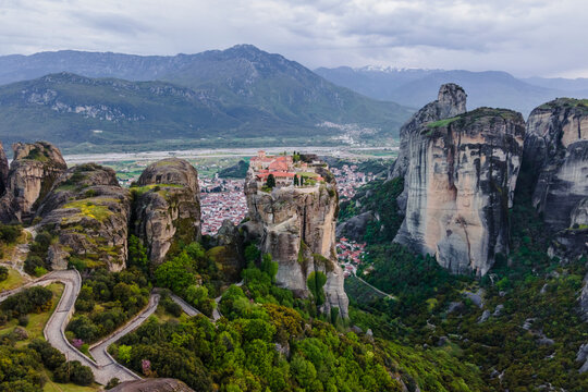 Aerial view of The Holy Trinity Orthodox Monastery with Kalabaka town in background at sunset, Meteora, Kalabaka, Thessaly, Greece.
