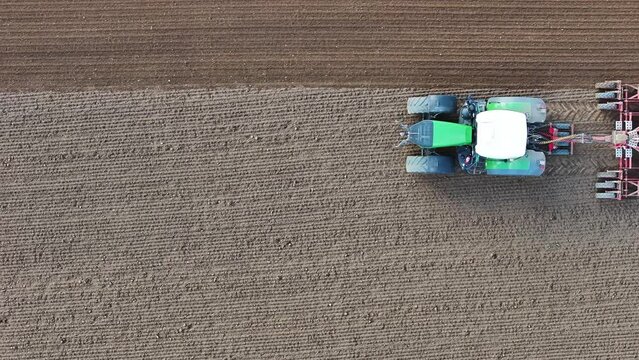 Aerial view of a thresher and a tractor, heavy duty machinery for agricultural farm working harvesting the grain in a field, Brandenburg, Germany.