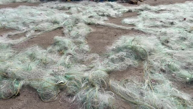 Fishing nets used to catch fish is spread across the sand for drying using sunlight