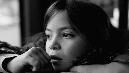 Melancholic pensive child closeup face in monochrome. Thoughtful small girl feeling sad in black...