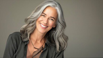 a clean studio portrait of a middle-aged caucasian woman with blond silver hair in white t-shirt looking into the camera smiling, grey background. - obrazy, fototapety, plakaty