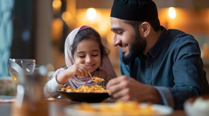 Happy Middle eastern father feeds his daughter during dinner at dining table on Ramadan. - obrazy, fototapety, plakaty