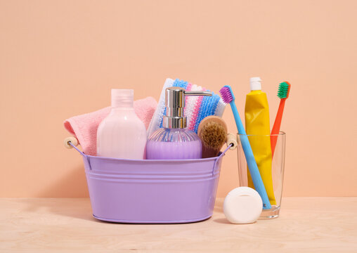 Composition of various hygienic supplies in a purple basin. Oral and dental care. Clean shower towel and various gels, soaps.