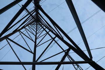Low angle shot of a high-voltage power line under a bright blue sky