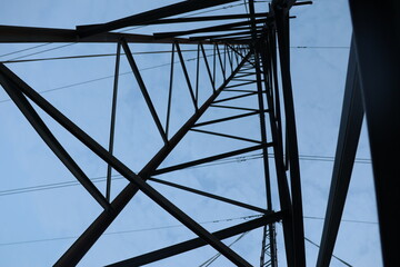 Low angle shot of a high-voltage power line under a bright blue sky - Powered by Adobe