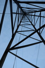 Low angle shot of a high-voltage power line under a bright blue sky