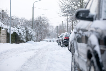 Snow piles on the street, uncleaned streets, cars parked on the side of the street