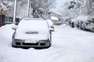 Snow-covered car in the street covered with a thick layer of snow on a winter day