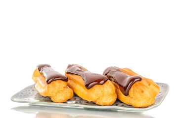 Three delicious chocolate eclairs on a ceramic saucer, close-up isolated on a white background.