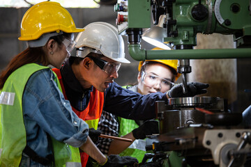Asian foreman manager showing case study of factory machine to two engineer trainee young woman in protective uniform. teamwork people training and working in industrial manufacturing business