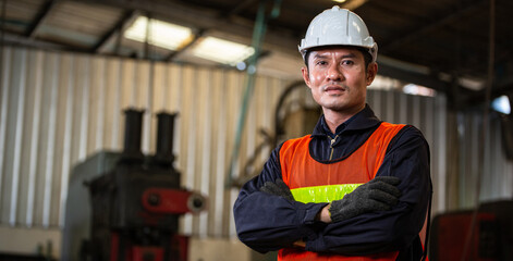 Asian male engineer foreman or construction worker in arms crossed looking at camera standing in...