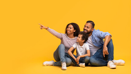 Family Offer. Happy Black Parents And Little Son Pointing At Copy Space