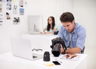 Camera, office and photographer looking at photoshoot in a studio or workshop for production. Creative, photography and young artist with dslr equipment for picture inspection in modern workplace.