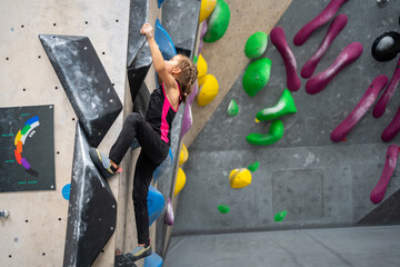 Full length of sporty little girl in active wear climbing artificial wall. Female child practicing...