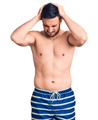 Fototapeta premium Young handsome man wearing swimwear suffering from headache desperate and stressed because pain and migraine. hands on head.