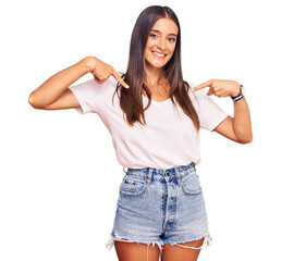 Young hispanic woman wearing casual white tshirt looking confident with smile on face, pointing oneself with fingers proud and happy.