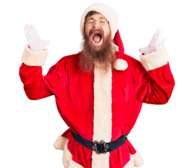 Handsome young red head man with long beard wearing santa claus costume celebrating mad and crazy for success with arms raised and closed eyes screaming excited. winner concept
