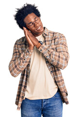 Handsome african american man with afro hair wearing casual clothes and glasses sleeping tired...