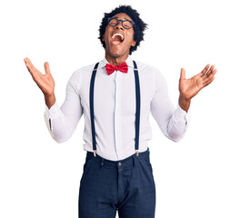 Handsome african american man with afro hair wearing hipster elegant look celebrating mad and crazy for success with arms raised and closed eyes screaming excited. winner concept