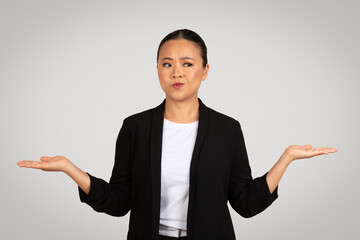 Perplexed Asian businesswoman with palms up in a questioning gesture, showing uncertainty