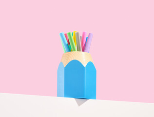 Blue pencil shaped stationery stand with multicolored markers. Bright school supplies composition.
