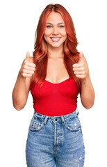 Young redhead woman wearing casual clothes success sign doing positive gesture with hand, thumbs up smiling and happy. cheerful expression and winner gesture.