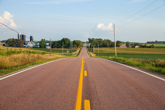 Rural road by a farm and fields in central Minnesota on a sunny afternoon during summer