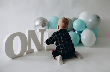 A boy on a white background with blue balloons. Child with balloons. First birthday. Holiday. Baby boss. Party