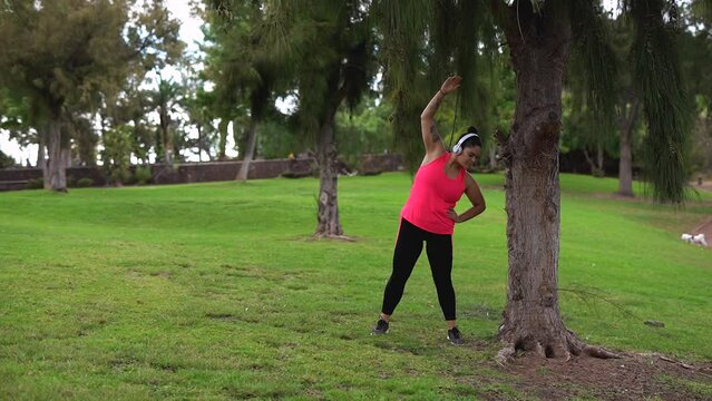 Curvy woman doing stretching exercise after running sport routine at city park