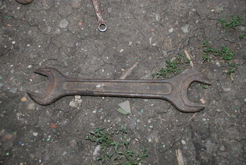 Big old wrench. There is an old rusty wrench lying on the ground. Due to rust, it is dark brown in...