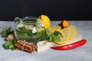 Herbal tea with mint, ginger, lemon and spices on textured background with copy space. Homemade medicine concept. Natural organic drink for cold period.
