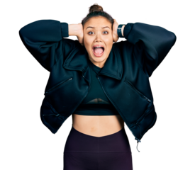 Young hispanic girl wearing sportswear crazy and scared with hands on head, afraid and surprised of shock with open mouth