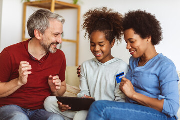 Family Using Digital Tablet And Credit Card At Home
