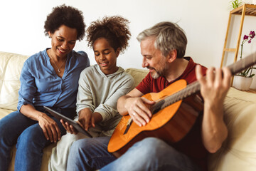 Man singing and playing guitar for his daughter and his wife. - obrazy, fototapety, plakaty